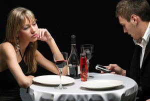 Una pareja cena en un restaurante y ella está aburrida mientras él mira su móvil